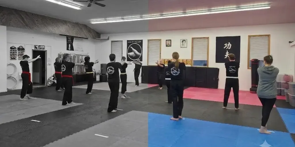 Group of martial arts students in black uniforms practice arm techniques in a dojo with tatami mats and banners on the wall.
